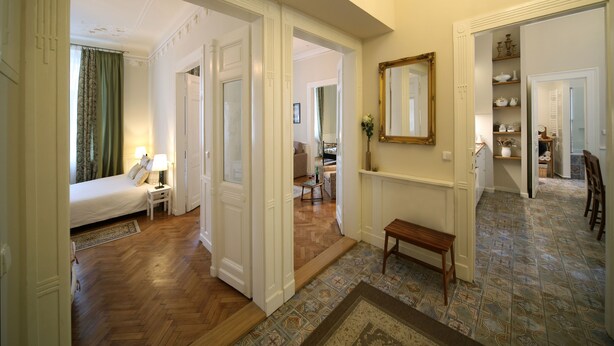 A hotel hallway with a bed, a bench, and a mirror on the wall.