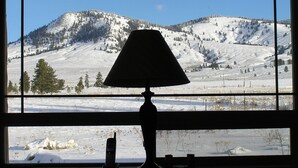 A window view of a snowy mountain landscape with a lamp in the foreground. - Ranch Style Cabin on 20 Acres in the Beautiful Tunk Valley (Riverside)