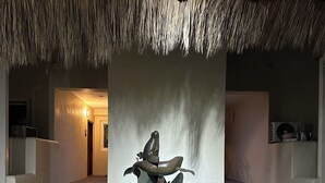 A circular water feature with a turtle sculpture, a thatched ceiling, and a staircase leading to an interior space.