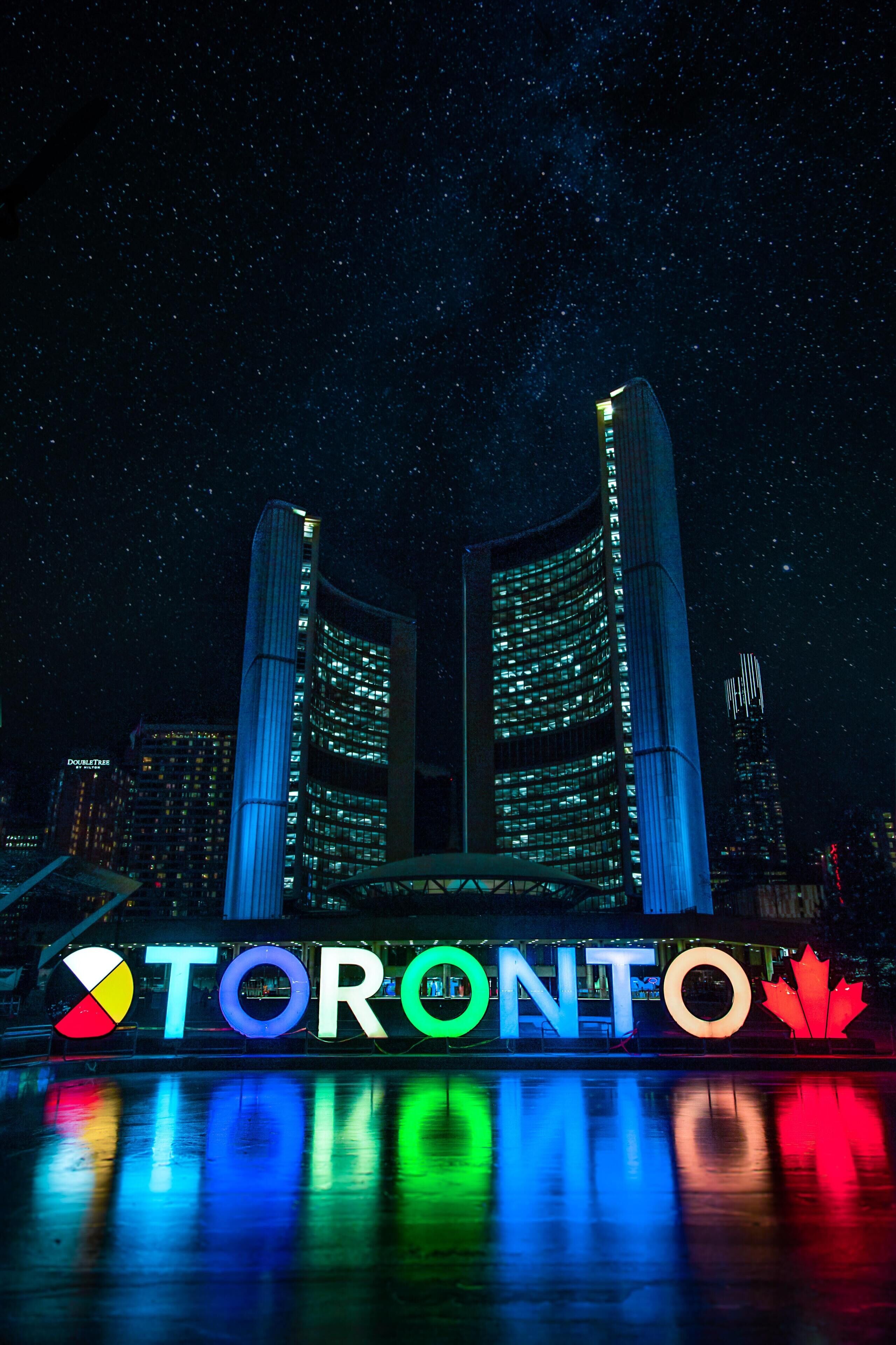 Vista nocturna de la Torre CN, con la palabra 'TORONTO' iluminada debajo.