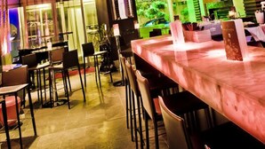 Eine Bar mit einer langen Theke, mehreren Tischen und Stühlen.