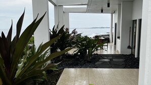 Ein überdachter Außenbereich mit Meerblick, ausgestattet mit Blumentöpfen und einem gefliesten Boden.