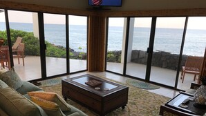 Ein geräumiges Wohnzimmer mit einem großen Schiebe-Glasfenster, das auf einen Balkon mit Meerblick führt.