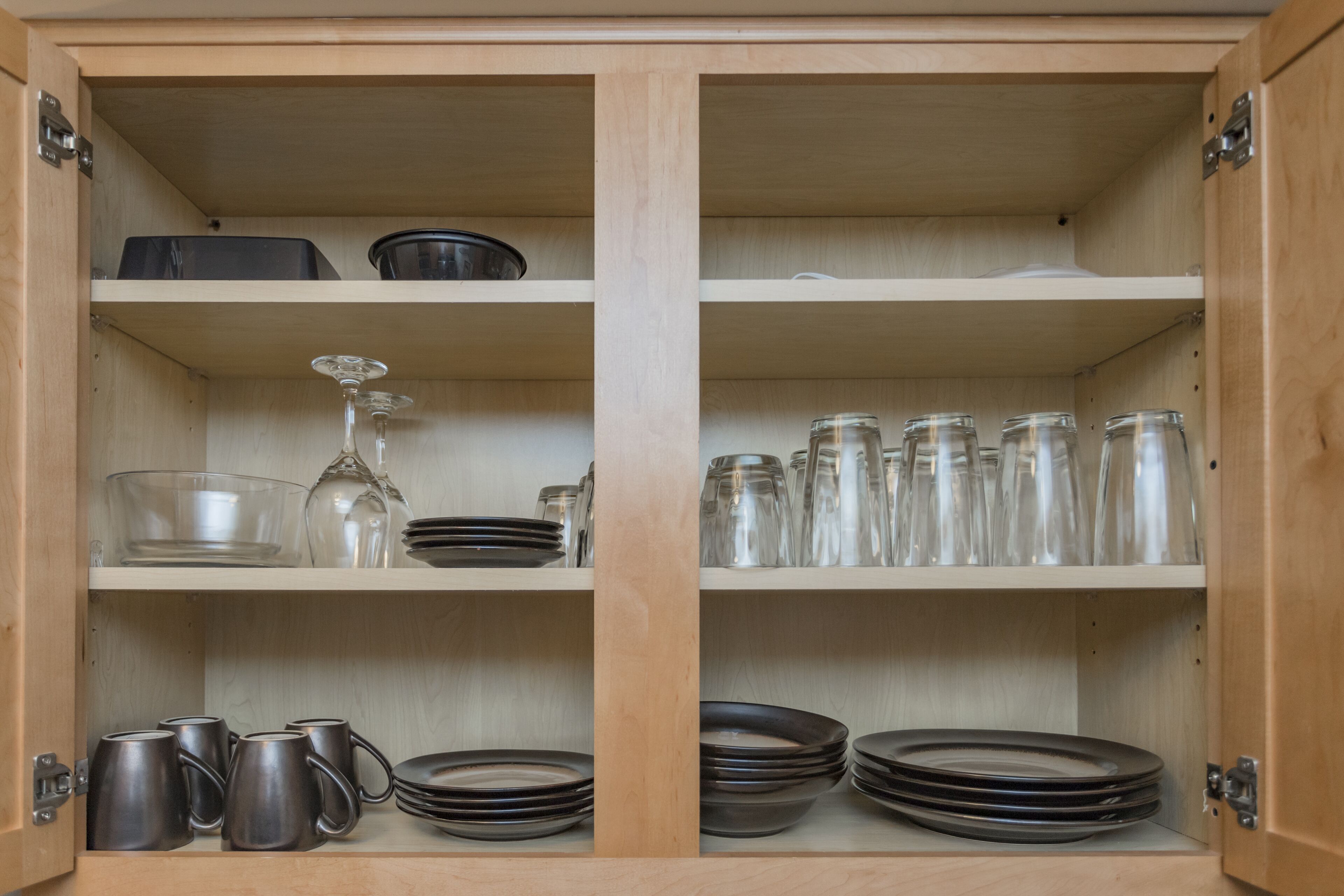 A wooden cabinet with shelves containing glassware, plates, and mugs.