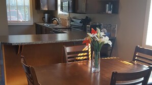 Una cocina moderna con armarios de madera oscura, una isla central y una zona de comedor con una mesa y sillas de madera.