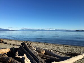 A calm lake with a clear sky, surrounded by mountains and a rocky shoreline.