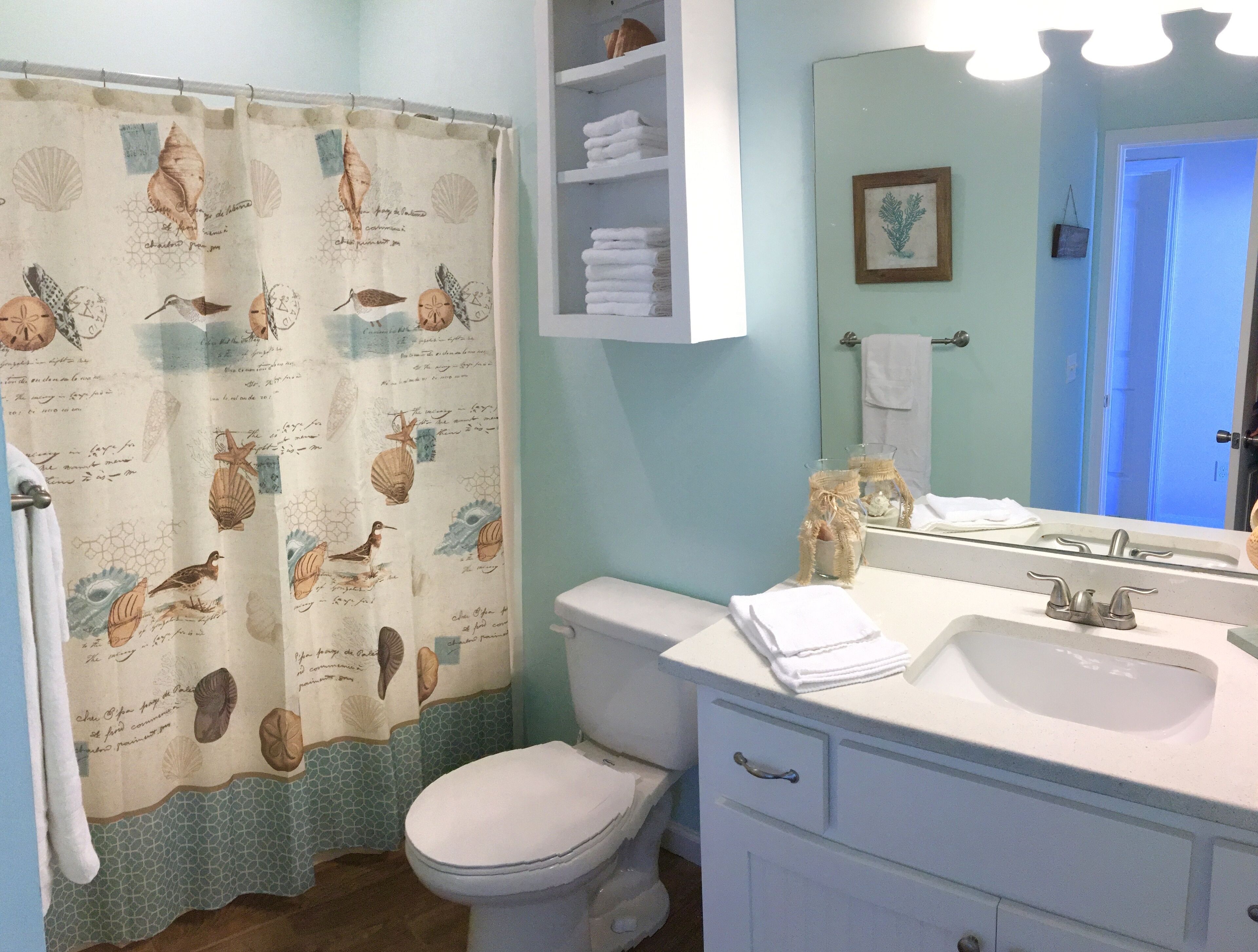 Un baño con inodoro, lavamanos y cortina de ducha con motivos de criaturas marinas.