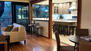 A modern interior with a dining area, kitchen, and a large window overlooking a tree.