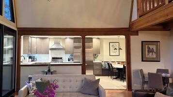 A modern interior with a sofa, dining area, kitchen, and staircase.