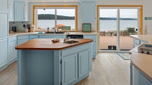 A kitchen with a large island, a view of a lake, and a deck area. - Spacious Beach Front Home on Hood Canal w/ Kayaks! (Belfair)