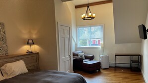 A bedroom with a bed, a chair, a table, and a window. - Recently Renovated In-Town Bar Harbor 4 Bed 3 Bth Apartment with Private Parking (Bar Harbor)