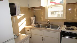 A kitchen with a microwave, coffee maker, sink, stove, and cabinets. - Come stay in our 2bd cabin on Table Rock Lake close to Silver Dollar City! (Branson)