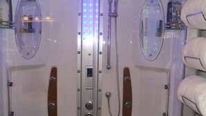 Ein Badezimmer mit zwei Duschkabinen, jeweils mit Spiegel, Duschbrausehandstück und Bedienfeld.