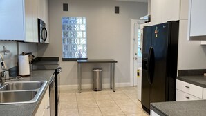 Una cucina moderna con elettrodomestici in acciaio inossidabile, una finestra con motivo geometrico e un cestino.