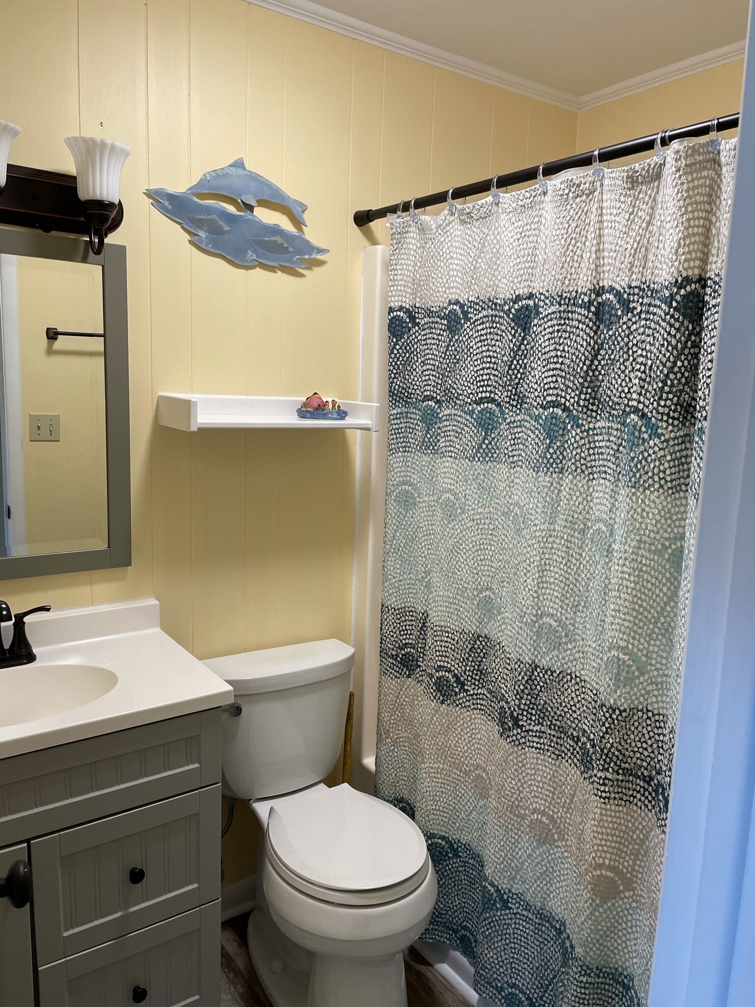 A bathroom with a toilet, sink, mirror, and a shower curtain.