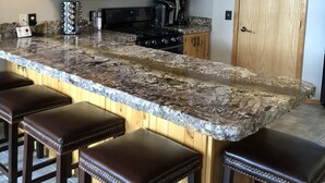 A kitchen with wooden cabinets, a granite countertop, and a stainless steel range hood.