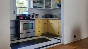 A kitchen with a stove, microwave, and yellow cabinets.