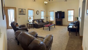 A living room with a fireplace, leather sofas, a television, and a clock on the wall.