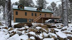 A lodge with a green roof, a covered deck, and a garage.