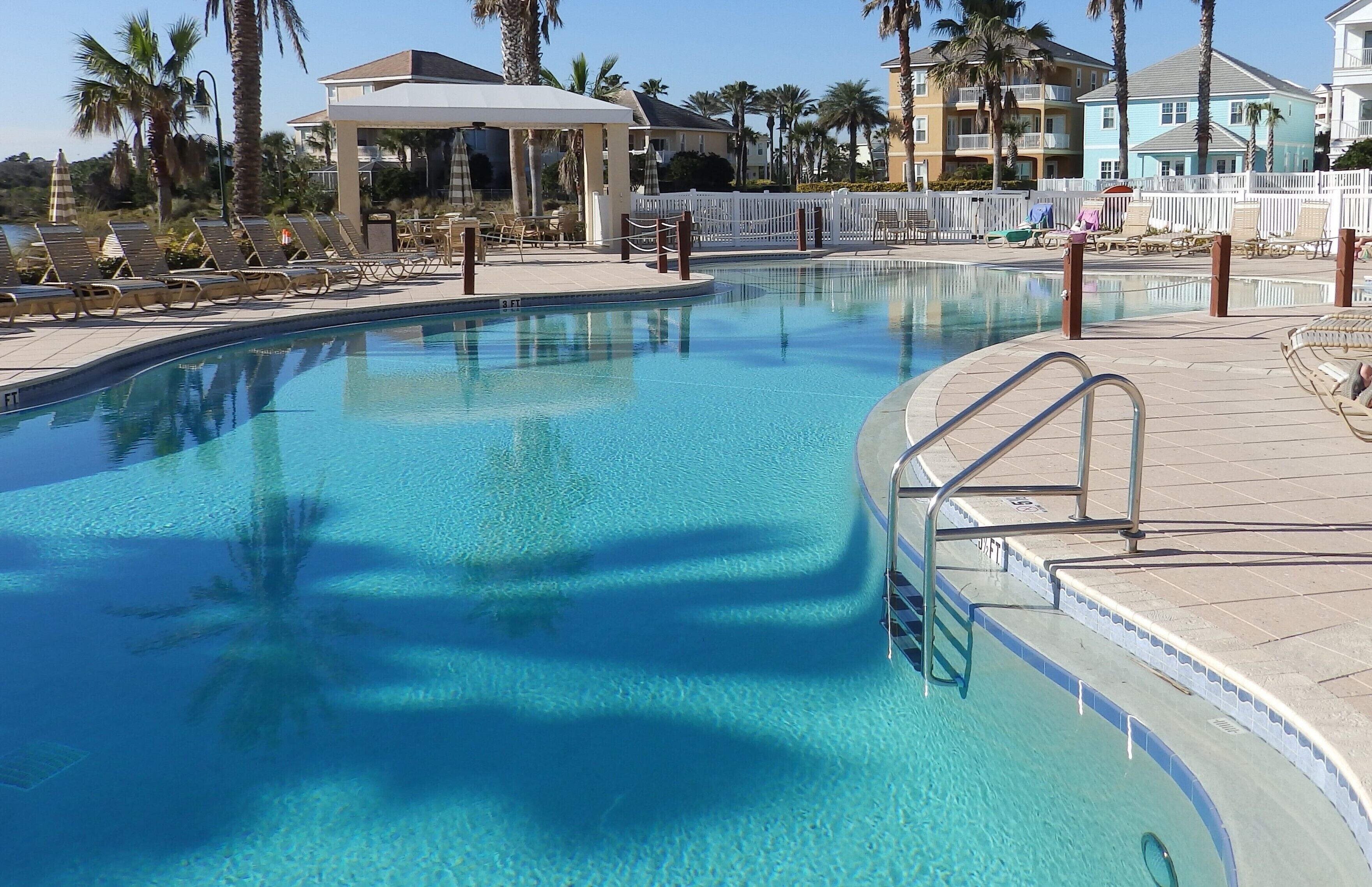 A swimming pool with lounge chairs and a covered seating area.