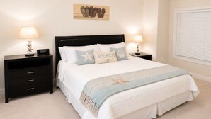 A bedroom with a bed, nightstands, a ceiling fan, a wall clock, and a window with blinds.