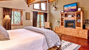 A cozy bedroom with a large bed, a fireplace, and a mounted deer head.