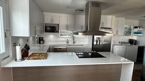 A modern kitchen with white cabinets, stainless steel appliances, and a central island. - Hacienda Margarita—Private Pool Spacious Home with VIEWS! (Luquillo)