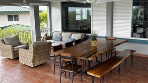 An outdoor patio with a wooden dining table, wicker chairs, and a bench. - Hacienda Margarita—Private Pool Spacious Home with VIEWS! (Luquillo)