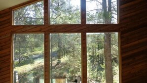 Habitación con grandes ventanales que ofrecen vistas a un área boscosa.