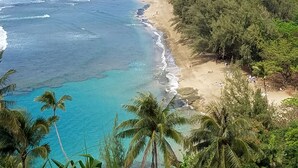 A beach with clear turquoise waters, a sandy shore, and dense green foliage. - BEAUTIFUL POIPU OCEAN VIEW 2 BRD 2.5 BATH Condo with A/C 
Great Fall Rates!
 (Koloa)