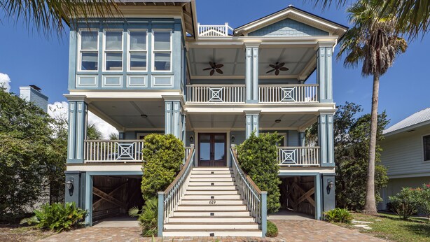 A two-story house with a front porch, a staircase, and a garage. - Spacious, Updated Home, Ocean Views, Pool, Elevator, Walk to Beach & Restaurants (Isle of Palms)