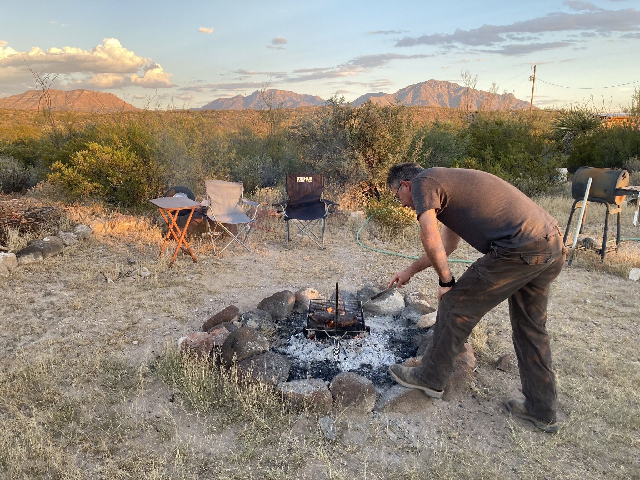 Guest cooking steak over campfire.