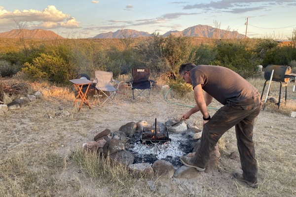 Guest cooking steak over campfire.