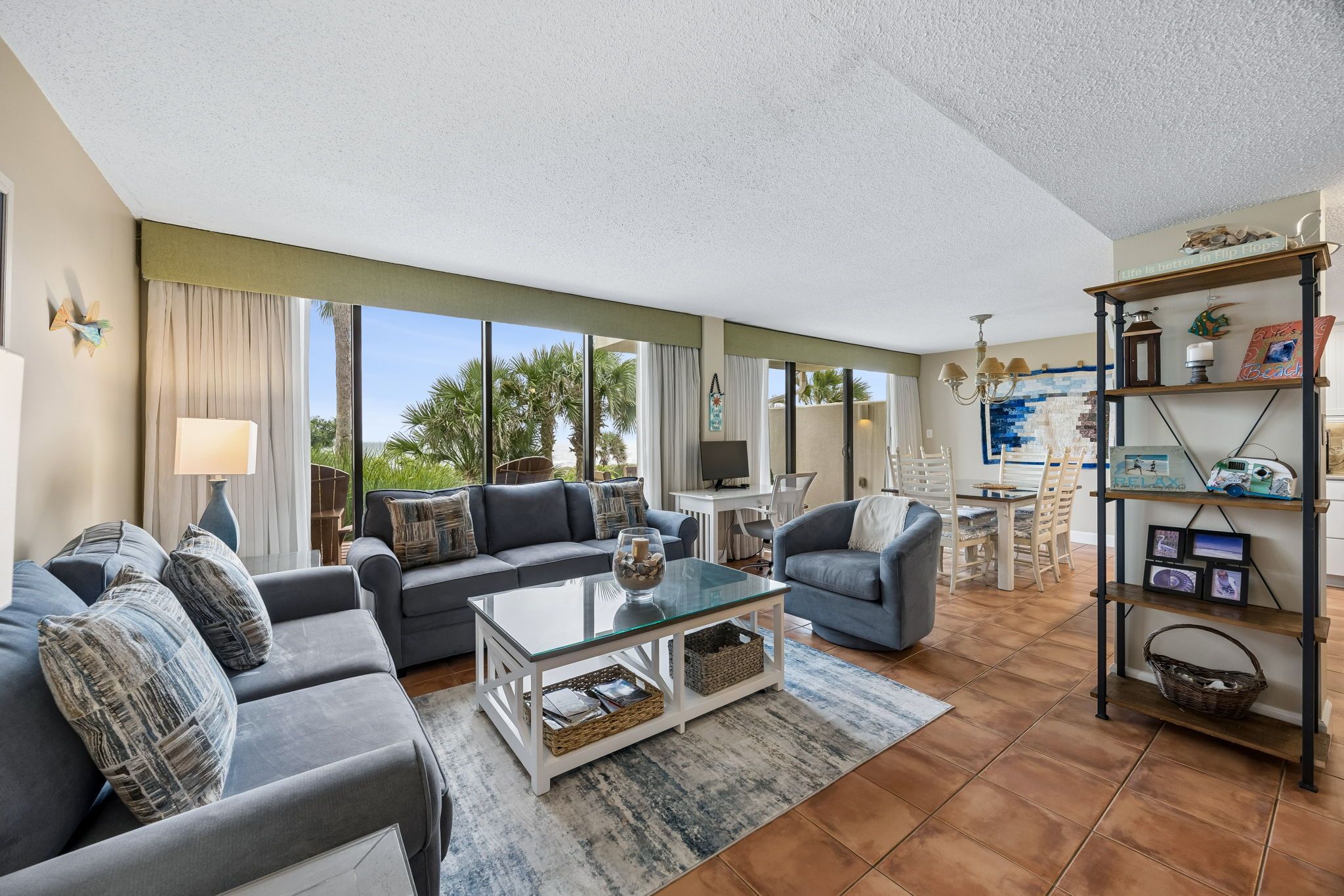 A spacious living room with a large window, a dining area, and a bookshelf.