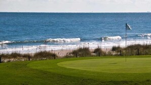 En golfbana med en flaggstång, en flagga och utsikt över havet.