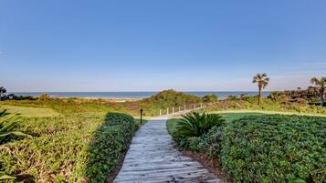 A wooden pathway leading to a beach with a clear sky.