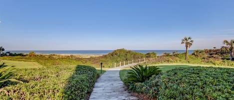 A wooden pathway leading to a beach with a clear sky.