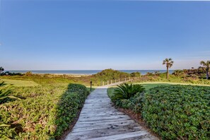 A wooden pathway leading to a beach with a clear sky.