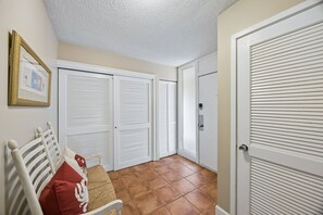 A hallway with white doors, a bench with a red pillow, and a framed picture on the wall.