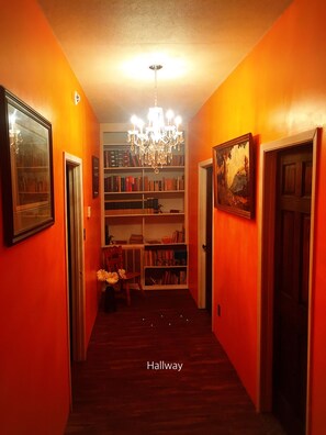 Ein Flur mit Bücherregalen, einem Chandelier und gerahmten Bildern an den Wänden.