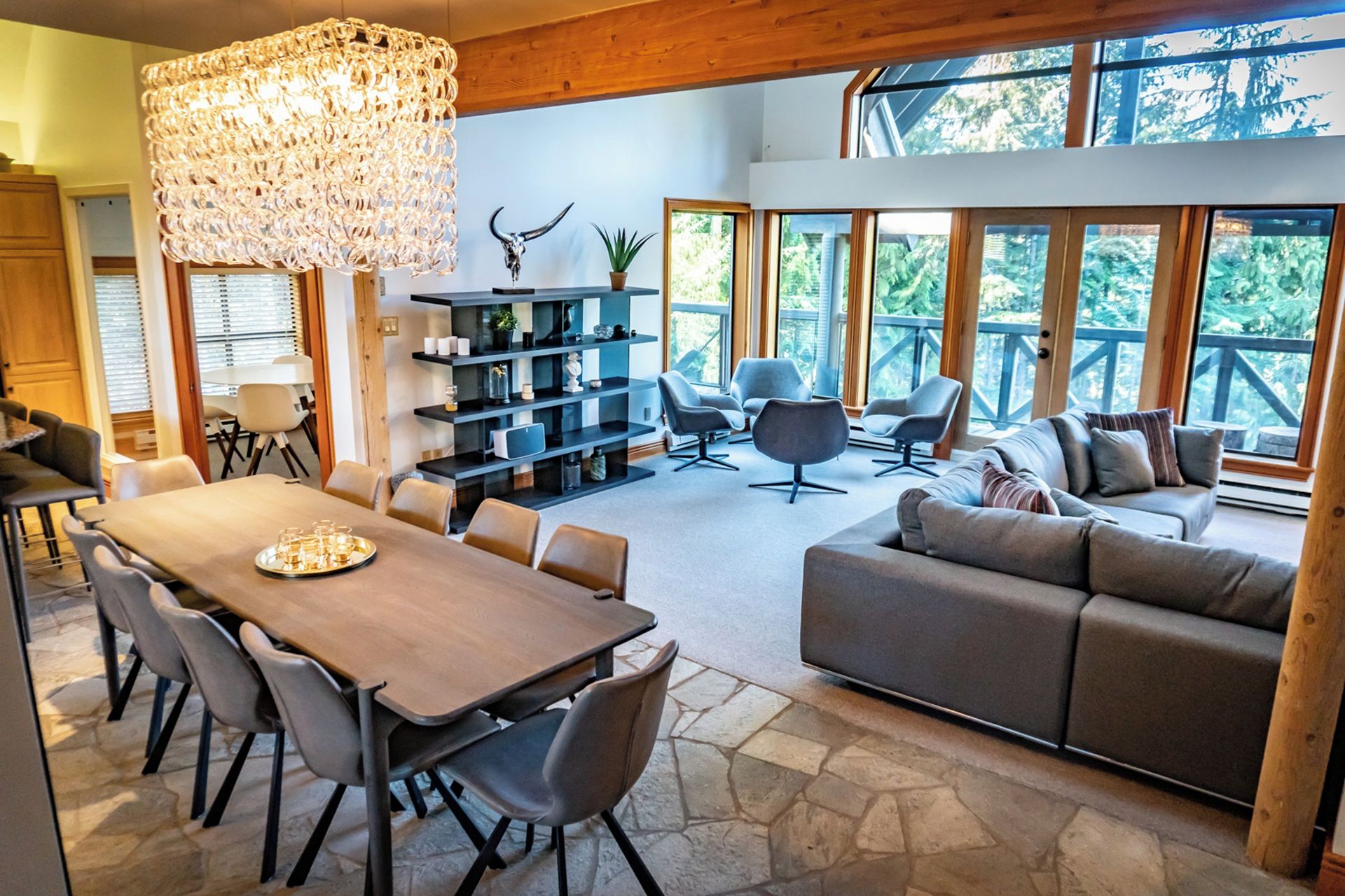 A spacious living area with a dining table, sofas, and a large chandelier.