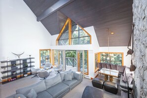Een moderne woonkamer met een grote grijze modulaire bank, een salontafel en een accentmuur van steen.