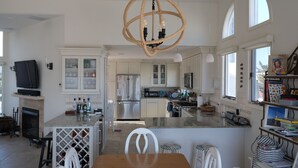 A spacious kitchen with a central island, a chandelier, and a dining area with a wooden table and chairs.