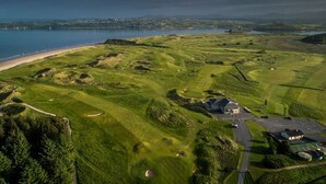 Vista aérea de un campo de golf con un club house, zona de estacionamiento y una playa.