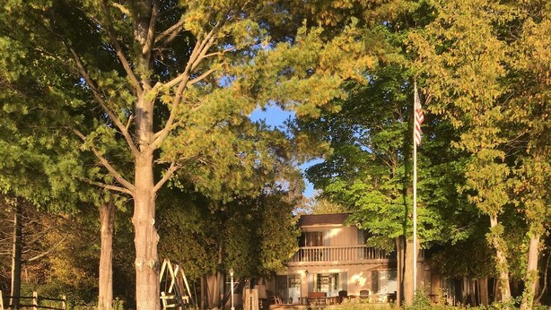 A wooden dock leading to a house by a calm river, surrounded by trees. - T.P.'S Place on the Stunning Aqua Blue Waters of Torch Lake (Bellaire)