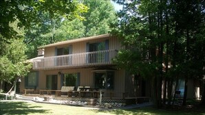 A two-story house with a balcony, a covered porch, and a well-maintained lawn. - T.P.'S Place on the Stunning Aqua Blue Waters of Torch Lake (Bellaire)