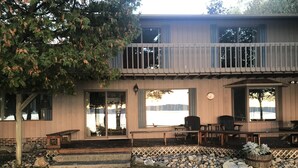 A two-story building with a balcony, large windows, and outdoor seating. - T.P.'S Place on the Stunning Aqua Blue Waters of Torch Lake (Bellaire)