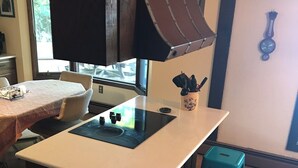 A kitchen with a central island, four teal stools, a window, and a clock on the wall. - T.P.'S Place on the Stunning Aqua Blue Waters of Torch Lake (Bellaire)