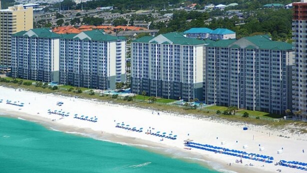 Un hotel frente a la playa con varios edificios de gran altura, una playa de arena y una zona de piscina.