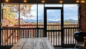 A wooden deck with a view of mountains and autumn foliage.